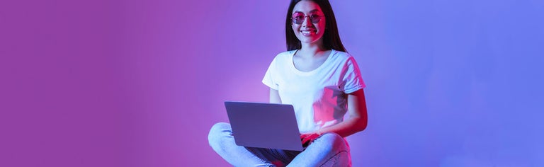 Woman using laptop against purple background