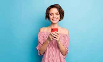 Young woman looking at smartphone against blue background