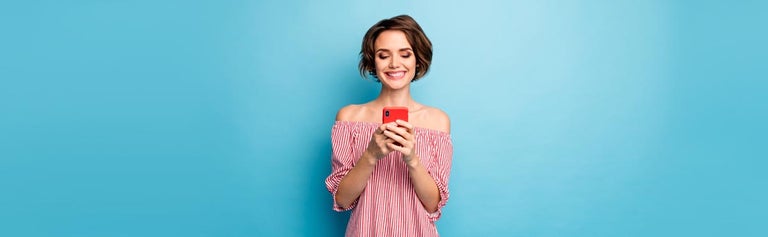 Young woman looking at smartphone against blue background