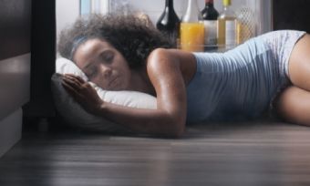 Young lady sleeping next to fridge in heatwave