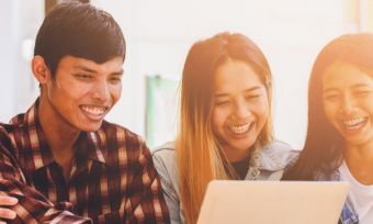 Young friends looking at laptop laughing in living room