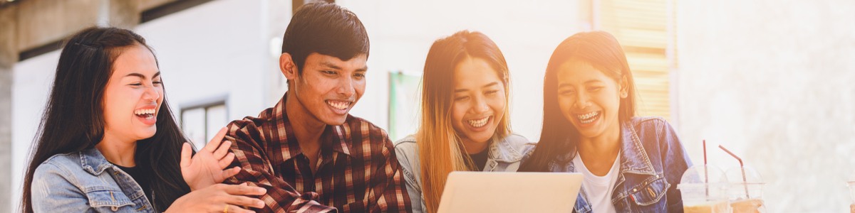 Young friends looking at laptop laughing in living room