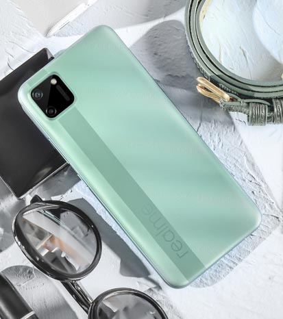 Realme C11 phone in green colour with random objects surrounding it