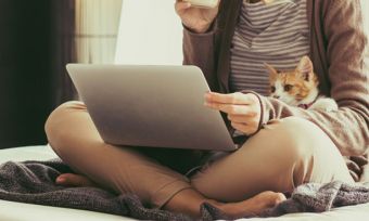 Woman using laptop with cat on lap