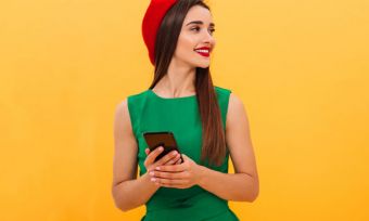 Young woman with phone wearing green dress and red beret
