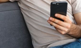 A man siting on a couch and using a phone