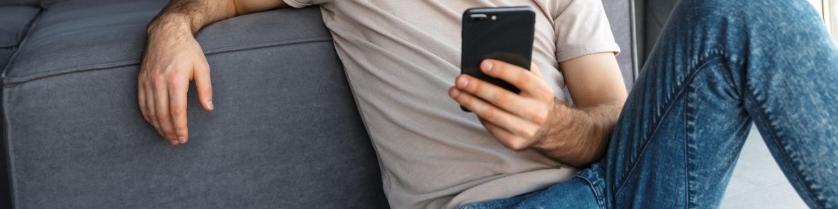 A man siting on a couch and using a phone