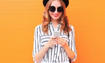 Woman using phone in front of orange wall