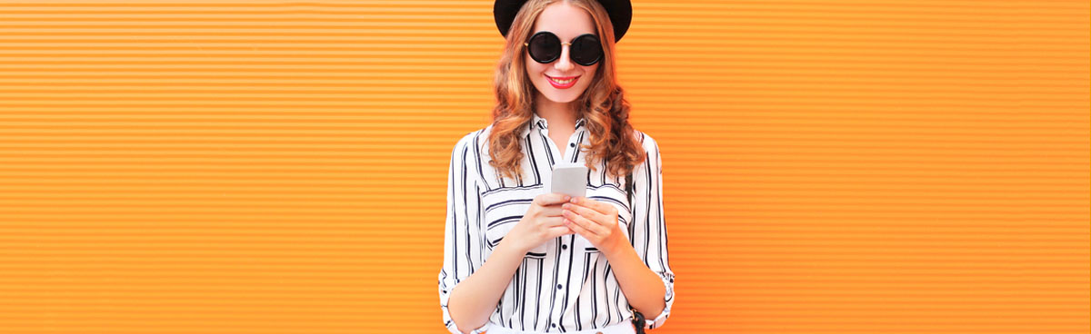 Woman using phone in front of orange wall