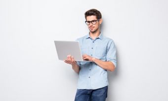 Young man looking at laptop computer against light grey background