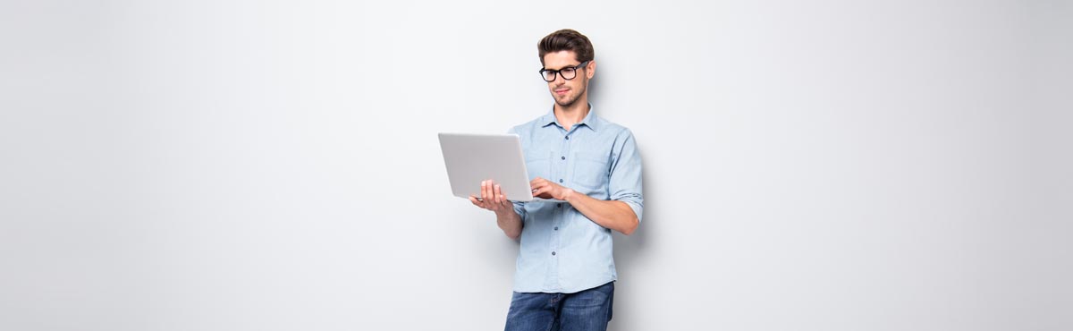 Young man looking at laptop computer against light grey background