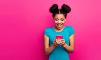Young woman looking at smartphone against pink background