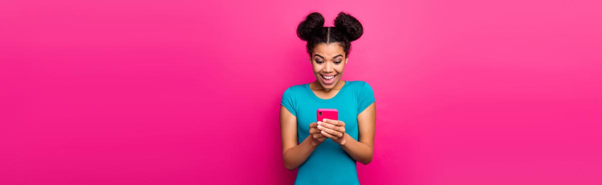 Young woman looking at smartphone against pink background