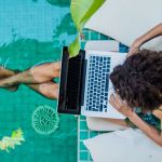 Overhead view of woman using laptop by pool