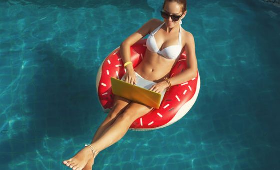 Woman floating in pool with laptop