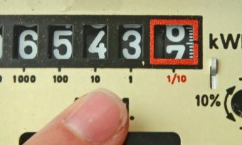 Electricity meter with finger pointing at numbers