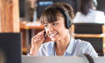 Lady working in call centre with headphone and mic on in front of computer