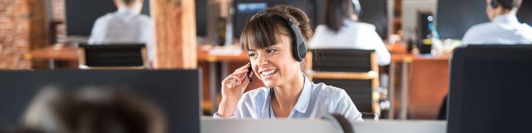 Lady working in call centre with headphone and mic on in front of computer