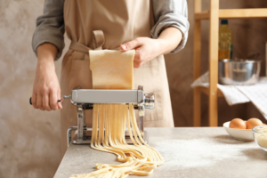 Person making pasta with a pasta making machine