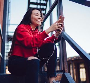 Young woman looking at phone while wearing headphones