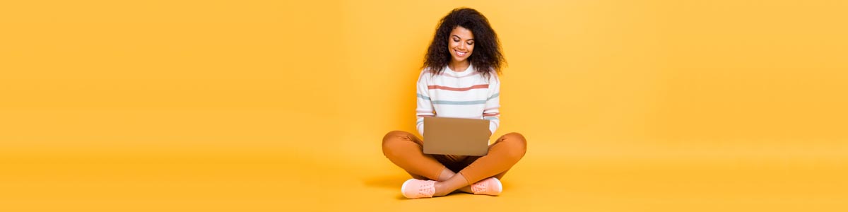 Young woman looking at laptop against yellow background