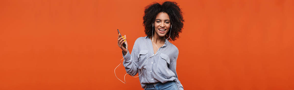 Young woman holding phone against orange background