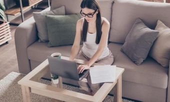 Woman sitting on couch looking at laptop computer in home