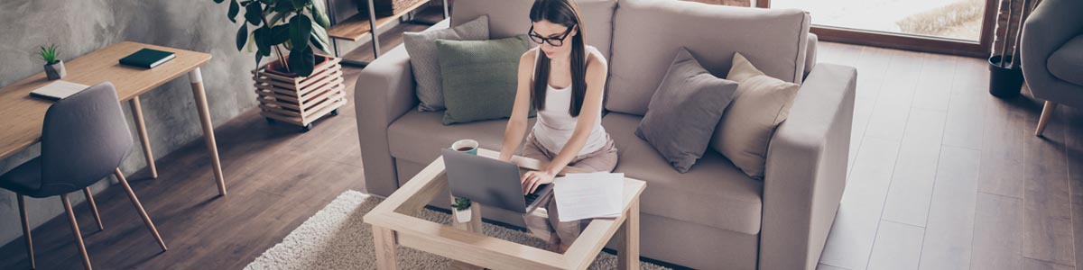 Woman sitting on couch looking at laptop computer in home