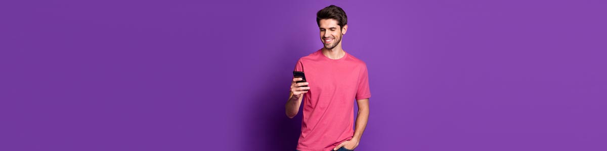 Young man looking at mobile phone against purple background