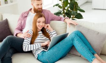 Happy young couple watching laptop on sofa