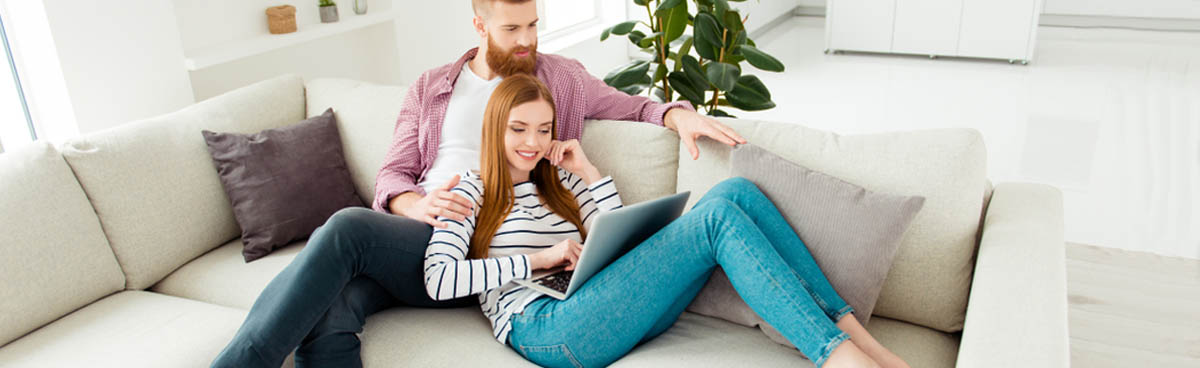 Happy young couple watching laptop on sofa