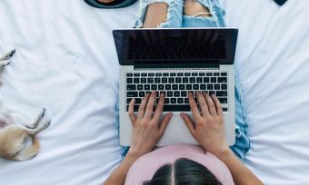 Woman at home using laptop on bed