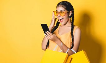 Young woman in yellow using mobile phone against yellow background