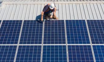 Technician installing solar panels on roof