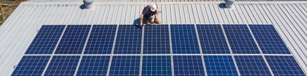 Technician installing solar panels on roof