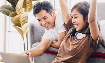 Young couple celebrate with laptop in home