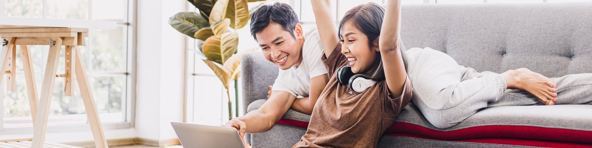 Young couple celebrate with laptop in home