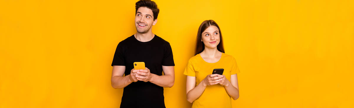 Young couple using phones against yellow background