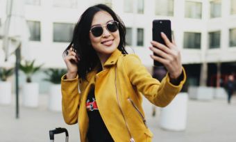 Young woman in yellow jacket using smartphone outdoors