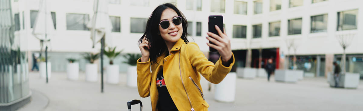 Young woman in yellow jacket using smartphone outdoors