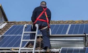 Technician installing solar panels on roof