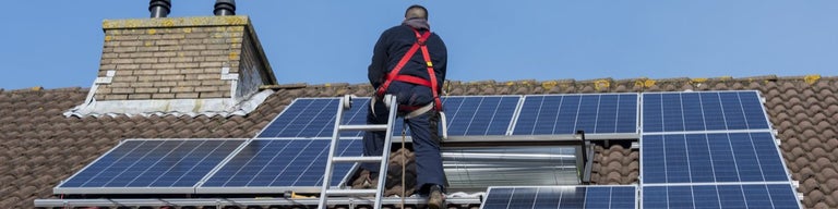 Technician installing solar panels on roof