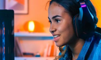 Young female gamer wearing headset playing computer game