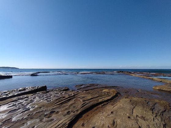 Wide angle photo of ocean and rock pools on clear day