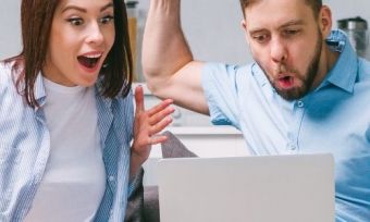 Two people using a laptop excitedly