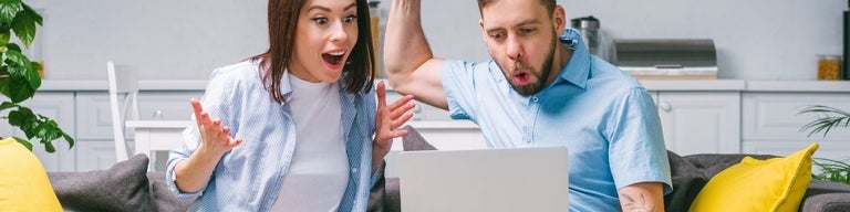 Two people using a laptop excitedly