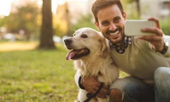 Smiling man posing for selfie with dog in park