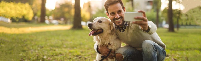 Smiling man posing for selfie with dog in park