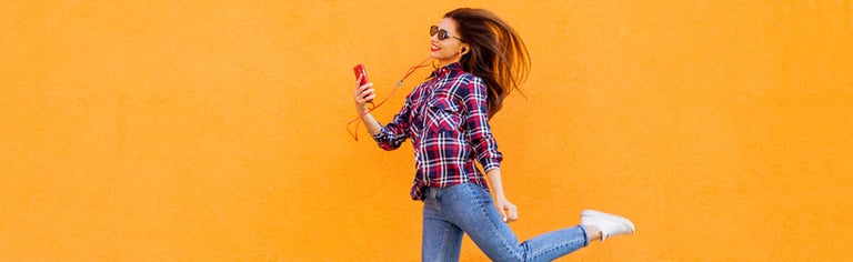 Young woman using smartphone against orange wall