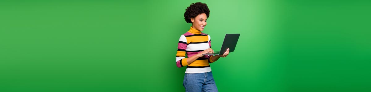 Young woman holding and looking at laptop against green background